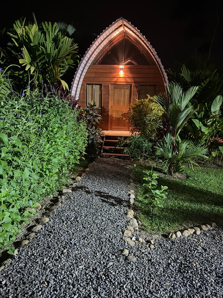 Wooden bungalow lit at night with gravel garden path